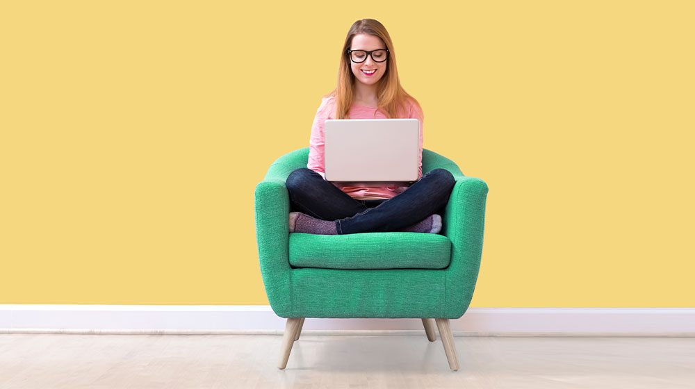 Frau sitzt auf einem Sofa und arbeitet an einem PC